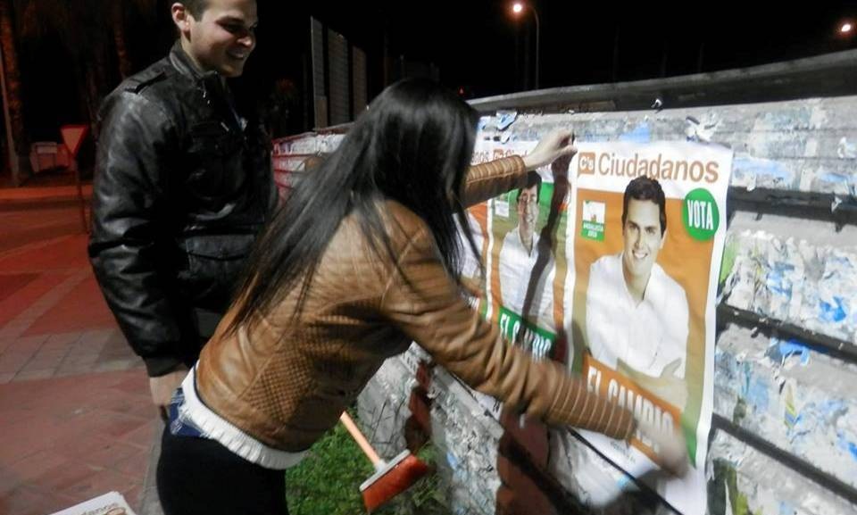 Una joven militante de Ciudadanos de Almuñécar colocando un cartel  para la campaña electoral al Parlamento de Andalucía