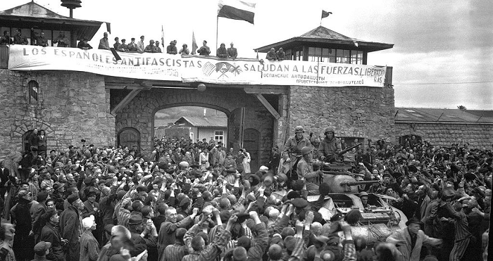 Prisioneros de Mauthausen saludan a la 11ª División Acorazada de los EE UU por su liberación bajo una pancarta escrita en español sobre sábanas castrenses